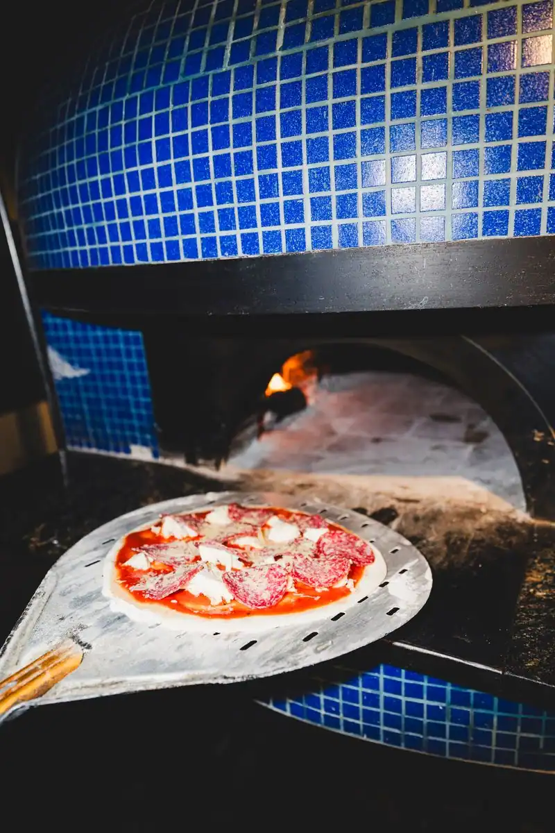 Roman pizza on the peel in front of Soler's blue-tiled wood-fired oven, Villa Crespo