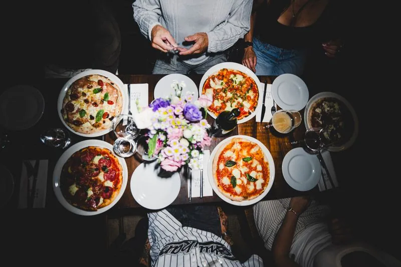 Mesa compartida con pizzas romanas y platos chicos en Soler Vino Pizza, Villa Crespo